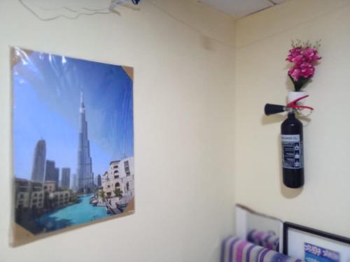 a vase of flowers on a wall with a picture at My Home Stay apartment 2 in Abu Dhabi