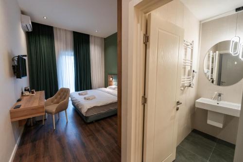Schlafzimmer mit einem Bett, einem Schreibtisch und einem Waschbecken in der Unterkunft Central Hotel Kutaisi in Kutaissi