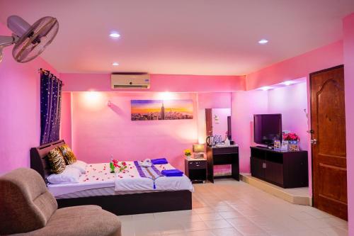 a bedroom with pink walls and a bed and a couch at Marine paradise Encore in Pattaya South
