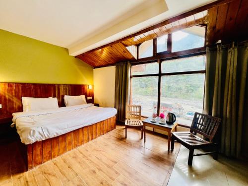 een slaapkamer met een bed en een groot raam bij Hotel Sliver Inn - Affordable Luxury Stay Near Mall Road in Manāli