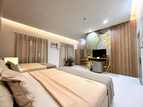 a bedroom with two beds and a flat screen tv at Hotel Nicanor in Dumaguete