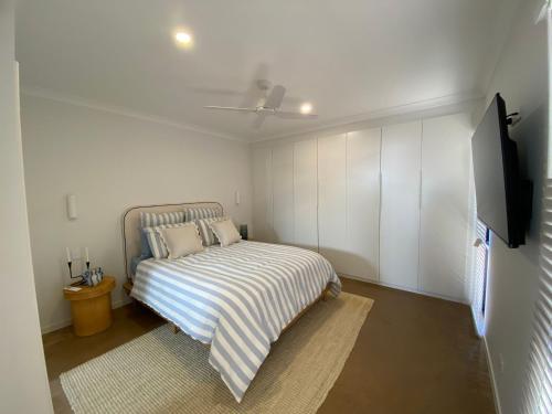 a white bedroom with a bed and a flat screen tv at 27 Bluefin Cove in Exmouth