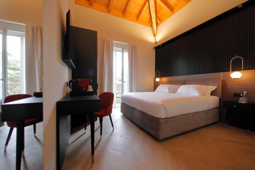 a bedroom with a bed and a desk and a television at Hotel Namia by Dori in Bardolino