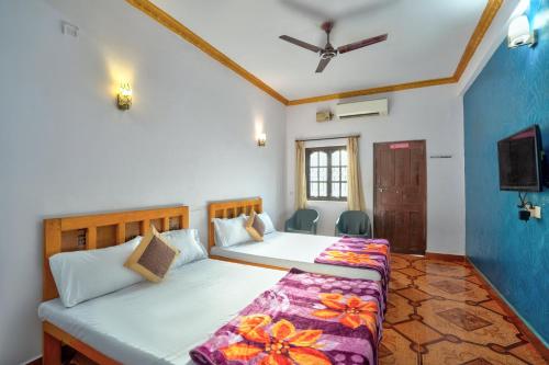 a bedroom with two beds and a tv at Baga Beach Walk in Baga