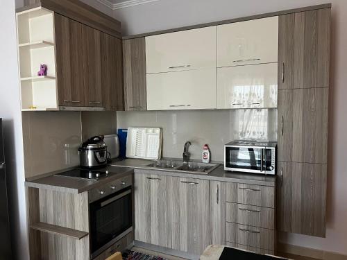 eine Küche mit Holzschränken, Spüle und Mikrowelle in der Unterkunft Dana’s home&sea in Vlorë