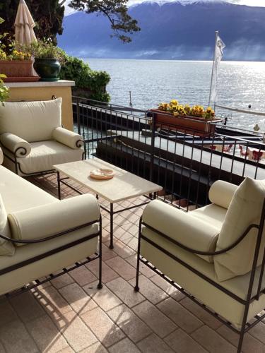 a patio with couches and a table and the water at Hotel Baia D'Oro - Adults Only in Gargnano