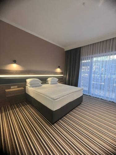 a bedroom with a large bed and a large window at Sapar Standart Улучшенный полулюкс in Shymkent