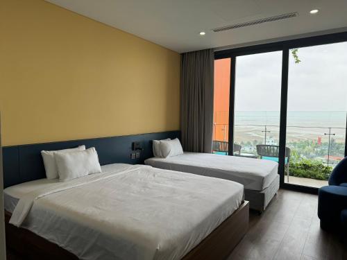 a hotel room with two beds and a large window at Flamingo Hải Tiến in Thanh Hóa