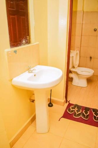 a bathroom with a white sink and a toilet at Modern one bedroom742333980 in Kisumu