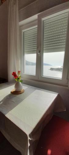 a table with a flower in a vase in a window at Direkt na moru - Bungalov in Šibenik