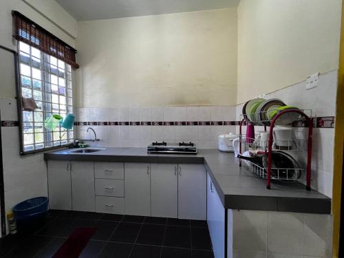 eine Küche mit weißen Schränken, einem Waschbecken und einem Fenster in der Unterkunft Dhiaa Homestay D Jembal in Kuala Terengganu