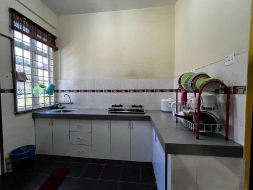 a kitchen with white cabinets and a sink and a window at Dhiaa Homestay D Jembal in Kuala Terengganu