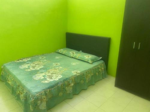 uma cama num quarto com uma parede verde em MyLittle Homestay em Tanjung Malim