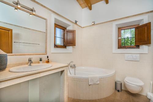 a bathroom with a tub and a sink and a toilet at Finca Puig Blanc by Sealand Villas in Muro