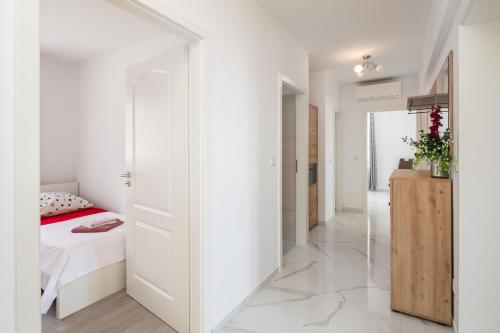 um quarto com paredes brancas e uma cama e um espelho em Paramount Apartments em Dugi Rat