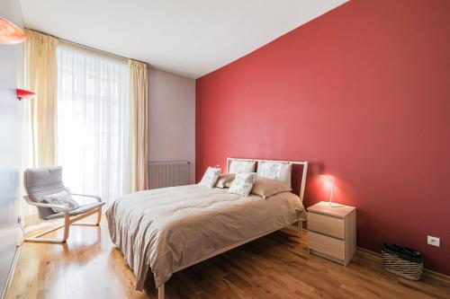 - une chambre dotée d'un mur rouge avec un lit et une chaise dans l'établissement Le Voltaire - Hypercentre - 185 m2 - Très haut de gamme - 2 sdb -2 wc, à Grenoble