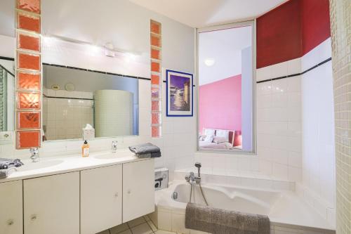 une salle de bain avec un lavabo, une baignoire et un miroir dans l'établissement Le Voltaire - Hypercentre - 185 m2 - Très haut de gamme - 2 sdb -2 wc, à Grenoble