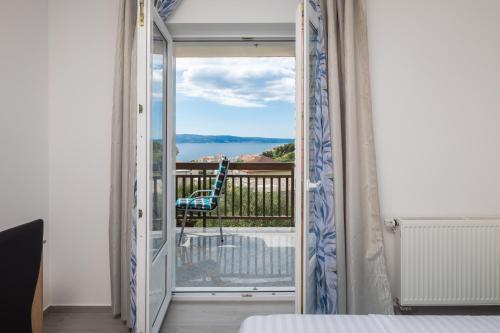 een kamer met een deur naar een balkon met een stoel bij Paramount Apartments in Dugi Rat