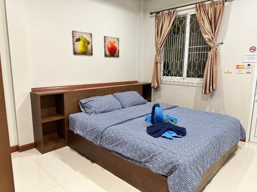 a bed with a blue stuffed animal sitting on it at Nuch's Apple Guest House in Si Bun Ruang
