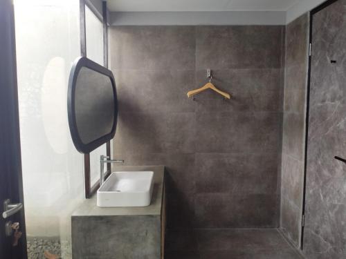 La salle de bains est pourvue d'un lavabo, d'une douche et d'un miroir. dans l'établissement Lynn Resort Carita, à Sukarame