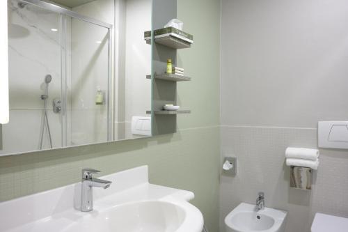 a bathroom with a sink and a shower and a mirror at Hotel Ilaria in Lucca