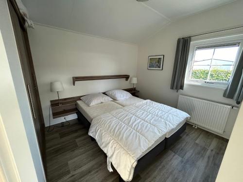 a bedroom with a large bed and a window at De Roos chalet 174 in Sint Annaland