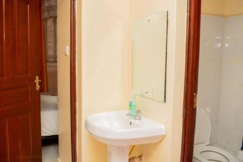 een badkamer met een wastafel, een toilet en een spiegel bij Kisumu 2bedroom in Kisumu