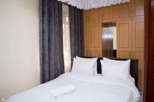 een bed met witte lakens en kussens in een kamer bij Kisumu 2bedroom in Kisumu