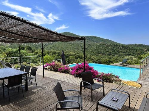 un patio avec une table et des chaises et une piscine dans l'établissement Villa CORAIL privée et climatisée pour 10 personnes avec piscine et superbe vue mer et collines à La Londe-les-Maures, à La Londe-les-Maures