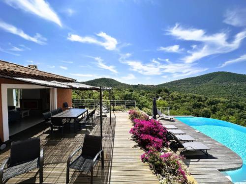 une terrasse avec une table et des chaises ainsi qu'une piscine dans l'établissement Villa CORAIL privée et climatisée pour 10 personnes avec piscine et superbe vue mer et collines à La Londe-les-Maures, à La Londe-les-Maures