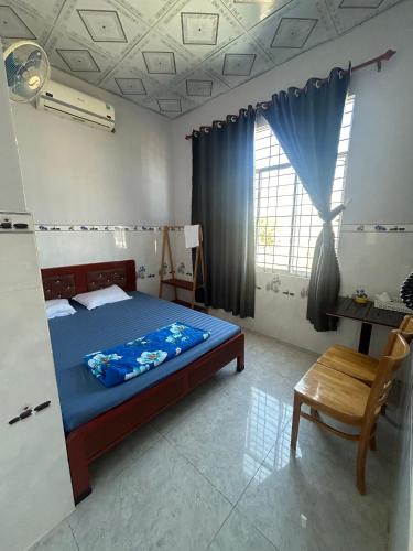 a bedroom with a bed and a chair and a window at Phòng Trọ Vân Anh in Ha Tien