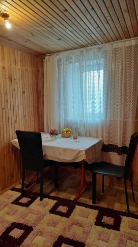 mesa de comedor con 2 sillas y ventana en Wooden room in garden house, en Najicheván