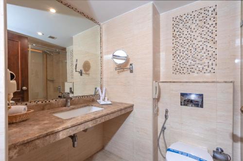 a bathroom with a sink and a toilet and a mirror at The Saibaba Hotel in Chennai