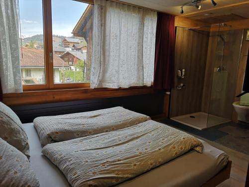 a bedroom with two beds and a window with a shower at Ritterstübli in Hasliberg