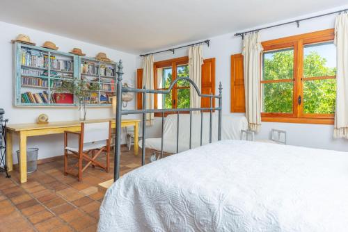 a bedroom with a bed and a desk and windows at Casa S'Olivaret -Selva- in El Port de la Selva