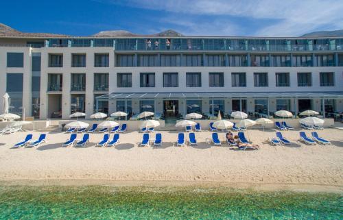 een groep stoelen en parasols op een strand bij Admiral Grand Hotel in Slano