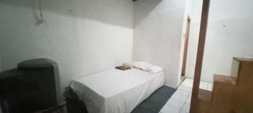 a small white room with a bed and a television at SPOT ON 93964 Guest House Pak Gatot 3 in Bandung