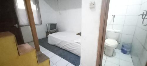 a small bedroom with a bed and a toilet at SPOT ON 93964 Guest House Pak Gatot 3 in Bandung