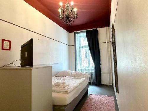 a bedroom with a bed and a television and a chandelier at Very Central, 5 min to city center, Self Check In in Vienna