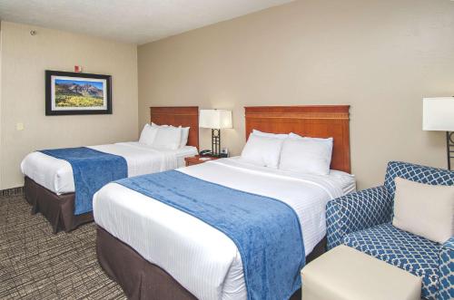 a hotel room with two beds and a chair at Best Western Timpanogos Inn in Lehi
