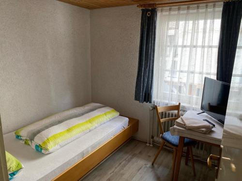 a small bedroom with a bed and a desk and a television at Zur Linde in Mühlheim an der Donau