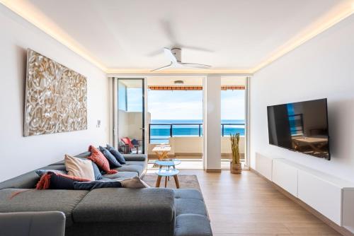 ein Wohnzimmer mit einem Sofa und einem Flachbild-TV in der Unterkunft BEACHFRONT -- NEW LUXURY Apartment -- 1ª Linea Playa -- Fuengirola CITY CENTER -- Private PARKING -- Panoramic Sea Views -- in Fuengirola
