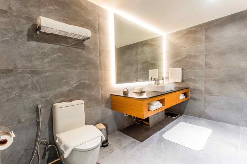 a bathroom with a toilet and a sink and a mirror at Brittany Hotel Villar City in Cavite