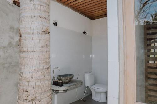 a bathroom with a toilet and a tree in it at Anugerah Surf & Dive in Nembrala