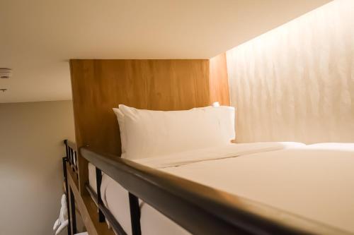 a bed with white sheets and a wooden headboard at Brittany Hotel Villar City in Cavite