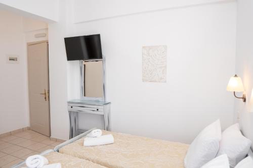 a white room with a bed and a television at ARTEMIS beach studios in Kalamaki Heraklion