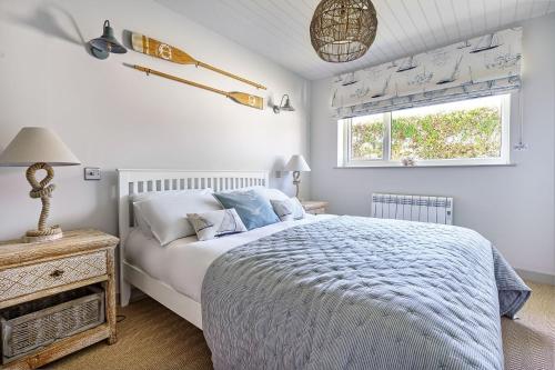 a white bedroom with a bed and a window at Gwendy in Abersoch