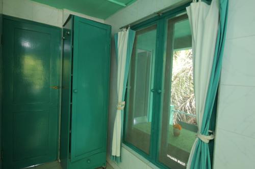 ein Badezimmer mit grünen Türen und einem Fenster in der Unterkunft Belvilla 93915 Bamboo Villa Near Central Ubud in Ubud