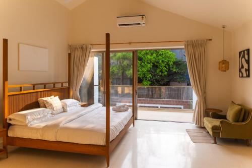 オールド･ゴアにあるApricus Villa Ambica Anjunaのベッドルーム1室(ベッド1台付)、スライド式ガラスドアが備わります。