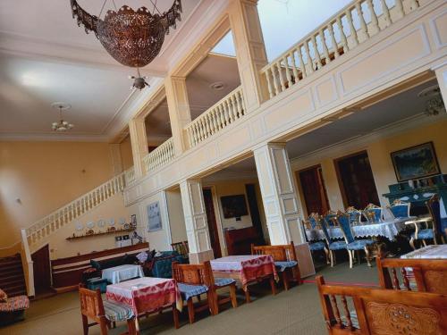 a dining room with tables and chairs and a staircase at Guest House Ikathouse in Margilan